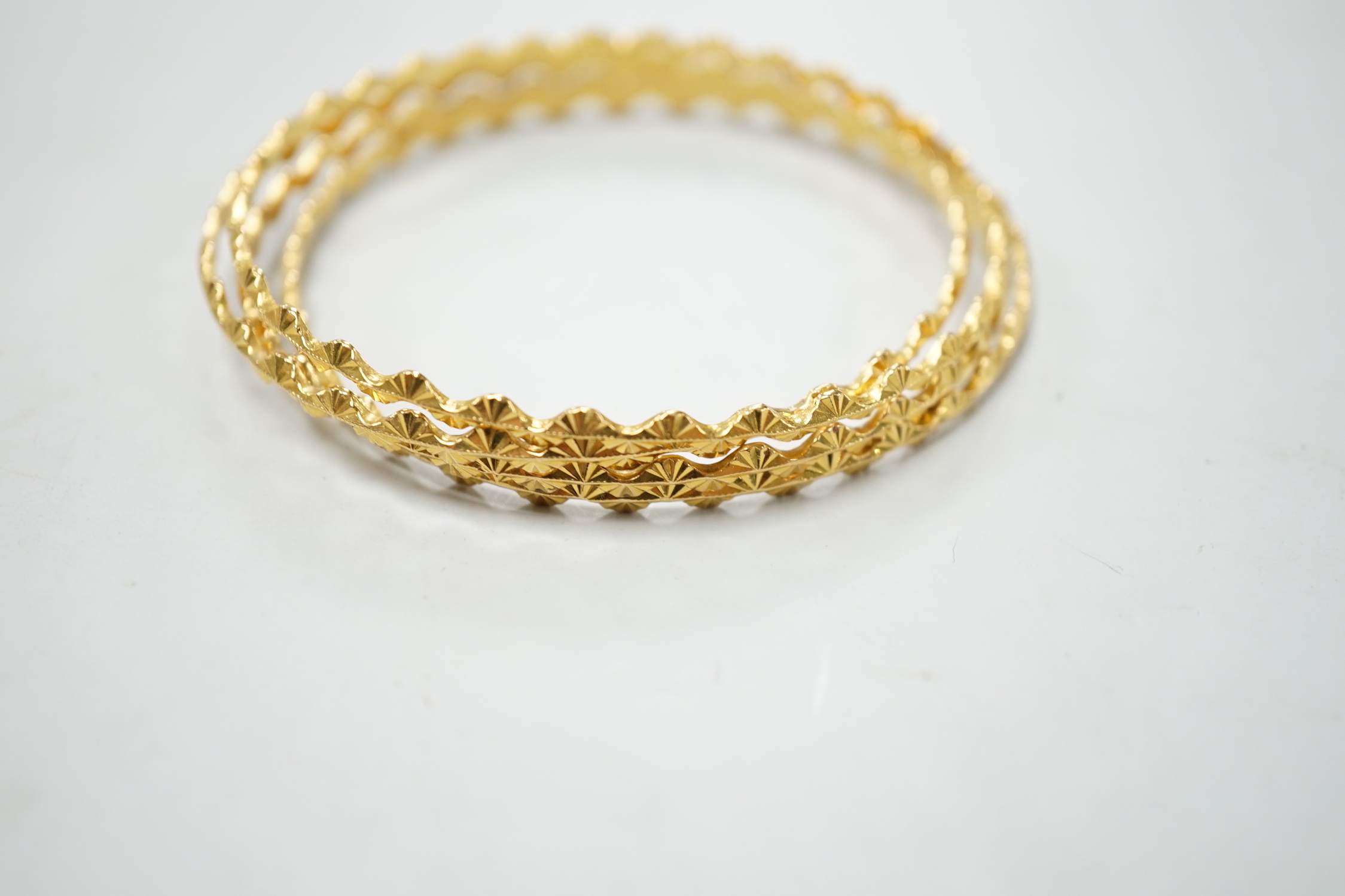 A set of four bright cut yellow metal bangles, with wavy border 34 grams.